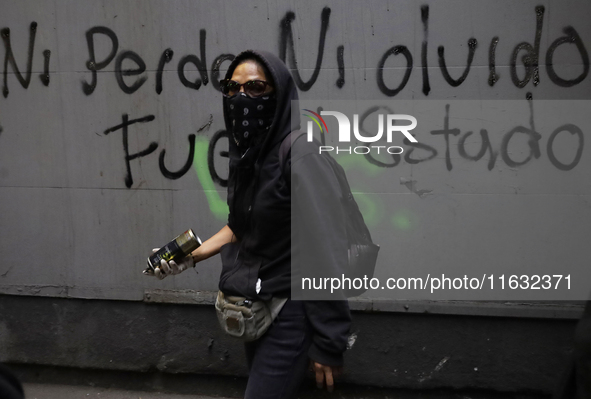 Members of the Anarchist Black Bloc paint graffiti during the march to mark the 56th anniversary of the Tlatelolco Massacre that occurs on O...