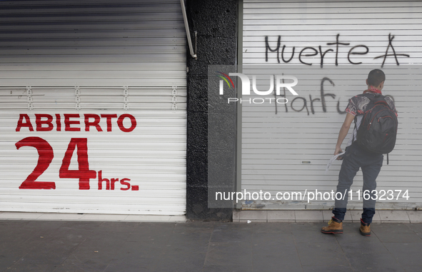 Members of the Anarchist Black Bloc paint graffiti during the march to mark the 56th anniversary of the Tlatelolco Massacre that occurred on...