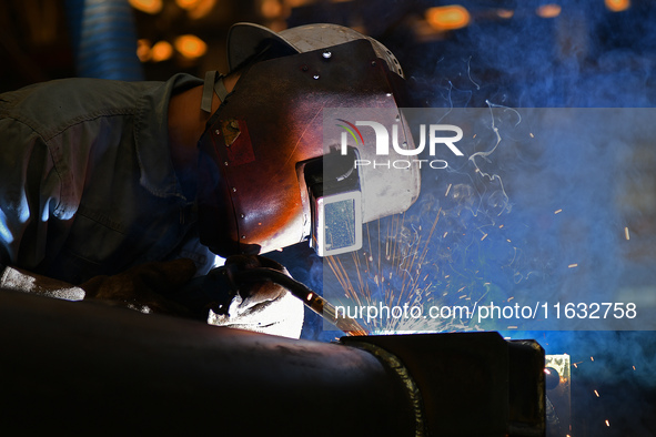 A worker performs welding at the assembly workshop of Ebara Cooling and Heating Systems (China) Co., LTD in Fushan district of Yantai city,...