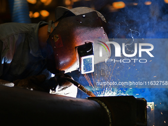 A worker performs welding at the assembly workshop of Ebara Cooling and Heating Systems (China) Co., LTD in Fushan district of Yantai city,...