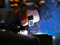 A worker performs welding at the assembly workshop of Ebara Cooling and Heating Systems (China) Co., LTD in Fushan district of Yantai city,...