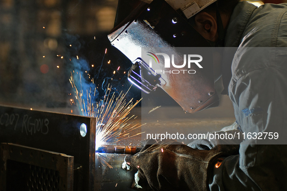 A worker performs welding at the assembly workshop of Ebara Cooling and Heating Systems (China) Co., LTD in Fushan district of Yantai city,...