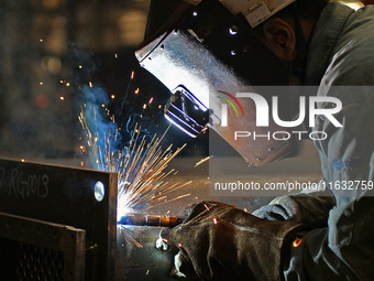 A worker performs welding at the assembly workshop of Ebara Cooling and Heating Systems (China) Co., LTD in Fushan district of Yantai city,...