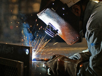 A worker performs welding at the assembly workshop of Ebara Cooling and Heating Systems (China) Co., LTD in Fushan district of Yantai city,...