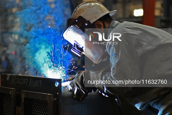 A worker performs welding at the assembly workshop of Ebara Cooling and Heating Systems (China) Co., LTD in Fushan district of Yantai city,...