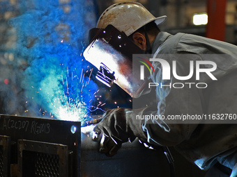 A worker performs welding at the assembly workshop of Ebara Cooling and Heating Systems (China) Co., LTD in Fushan district of Yantai city,...