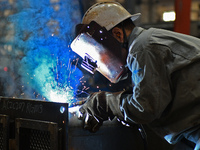 A worker performs welding at the assembly workshop of Ebara Cooling and Heating Systems (China) Co., LTD in Fushan district of Yantai city,...