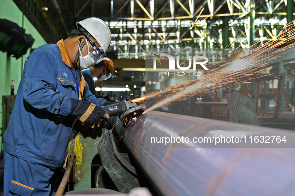 A worker carries out finishing work at a hot rolling workshop of Lubao Steel Pipe Co., LTD in the Fushan district of Yantai, China, on Octob...