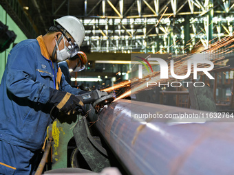 A worker carries out finishing work at a hot rolling workshop of Lubao Steel Pipe Co., LTD in the Fushan district of Yantai, China, on Octob...