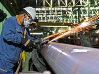 A worker carries out finishing work at a hot rolling workshop of Lubao Steel Pipe Co., LTD in the Fushan district of Yantai, China, on Octob...