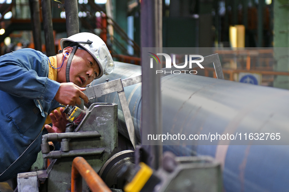 A worker checks steel pipes at a hot rolling workshop of Lubao Steel Pipe Co., LTD in the Fushan district of Yantai, China, on October 3, 20...