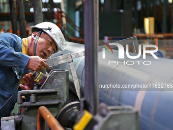 A worker checks steel pipes at a hot rolling workshop of Lubao Steel Pipe Co., LTD in the Fushan district of Yantai, China, on October 3, 20...