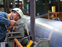 A worker checks steel pipes at a hot rolling workshop of Lubao Steel Pipe Co., LTD in the Fushan district of Yantai, China, on October 3, 20...