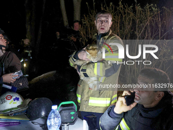 A rescuer holds a cat outside the residential building damaged by a Russian guided missile strike in Kharkiv, Ukraine, on September 3, 2024....