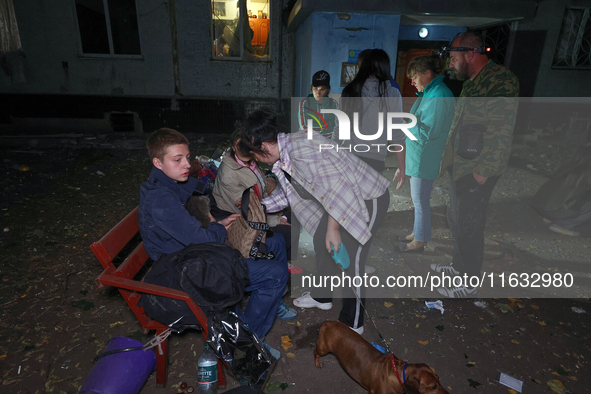 Local residents sit on the bench outside the apartment building damaged by a Russian guided missile strike in Kharkiv, Ukraine, on September...