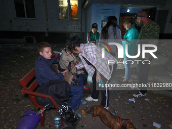 Local residents sit on the bench outside the apartment building damaged by a Russian guided missile strike in Kharkiv, Ukraine, on September...