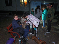 Local residents sit on the bench outside the apartment building damaged by a Russian guided missile strike in Kharkiv, Ukraine, on September...