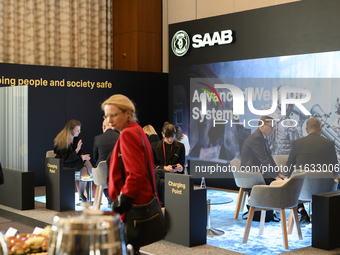 People sit at the SAAB AB lounge during the Warsaw Security Forum 2024 in Warsaw, Poland on October 2, 2024. WSF2024, entitled 'Ensuring Sec...