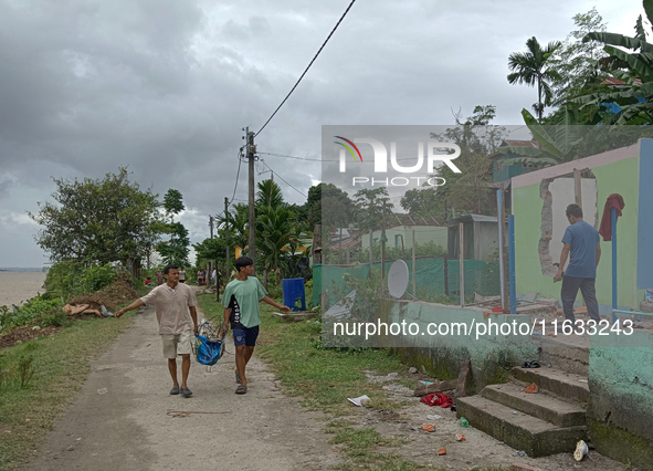 Villagers living in Laltong Village colony, approximately 20 km from Siliguri, carry their household items to a safer place on October 3, 20...