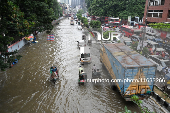 Vehicles and rickshaws try to drive with passengers through the waterlogged streets of Dhaka, Bangladesh, on October 3, 2024, after heavy mo...