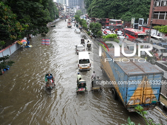 Vehicles and rickshaws try to drive with passengers through the waterlogged streets of Dhaka, Bangladesh, on October 3, 2024, after heavy mo...