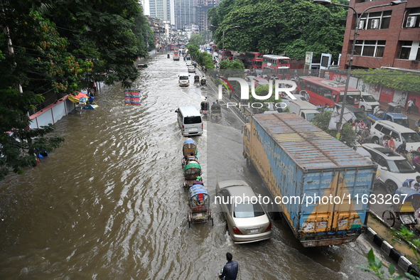 Vehicles and rickshaws try to drive with passengers through the waterlogged streets of Dhaka, Bangladesh, on October 3, 2024, after heavy mo...