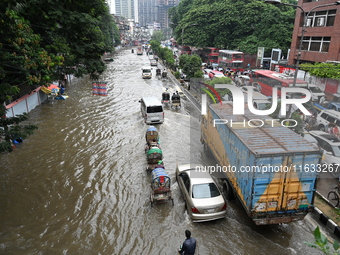 Vehicles and rickshaws try to drive with passengers through the waterlogged streets of Dhaka, Bangladesh, on October 3, 2024, after heavy mo...