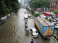 Vehicles and rickshaws try to drive with passengers through the waterlogged streets of Dhaka, Bangladesh, on October 3, 2024, after heavy mo...