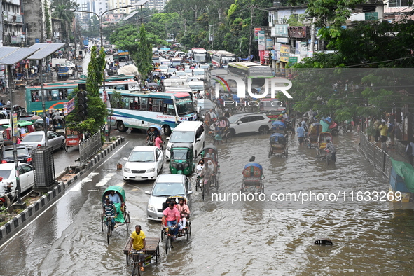 Vehicles and rickshaws try to drive with passengers through the waterlogged streets of Dhaka, Bangladesh, on October 3, 2024, after heavy mo...