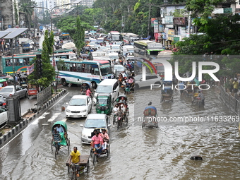 Vehicles and rickshaws try to drive with passengers through the waterlogged streets of Dhaka, Bangladesh, on October 3, 2024, after heavy mo...