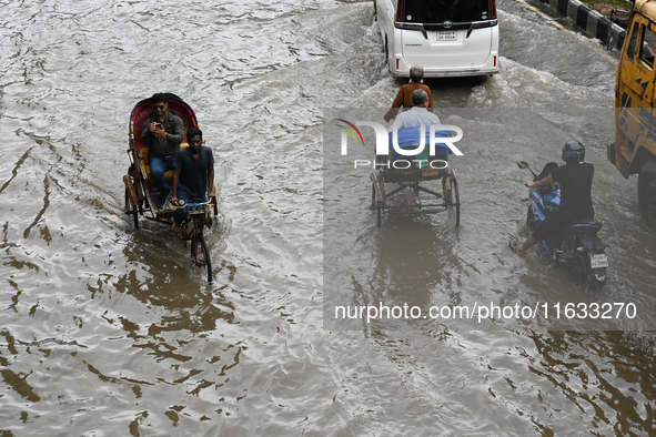 Vehicles and rickshaws try to drive with passengers through the waterlogged streets of Dhaka, Bangladesh, on October 3, 2024, after heavy mo...