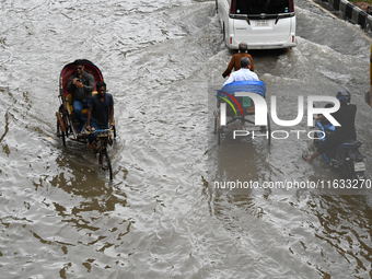 Vehicles and rickshaws try to drive with passengers through the waterlogged streets of Dhaka, Bangladesh, on October 3, 2024, after heavy mo...