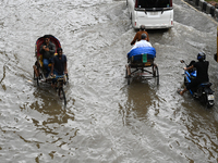 Vehicles and rickshaws try to drive with passengers through the waterlogged streets of Dhaka, Bangladesh, on October 3, 2024, after heavy mo...