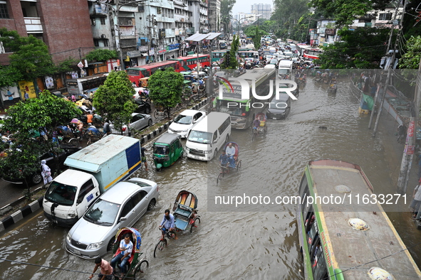 Vehicles and rickshaws try to drive with passengers through the waterlogged streets of Dhaka, Bangladesh, on October 3, 2024, after heavy mo...