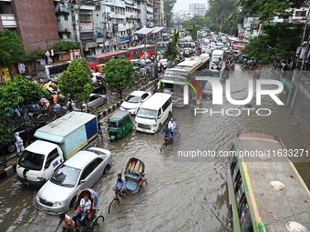 Vehicles and rickshaws try to drive with passengers through the waterlogged streets of Dhaka, Bangladesh, on October 3, 2024, after heavy mo...