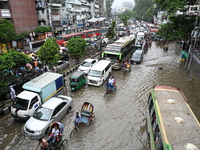 Vehicles and rickshaws try to drive with passengers through the waterlogged streets of Dhaka, Bangladesh, on October 3, 2024, after heavy mo...