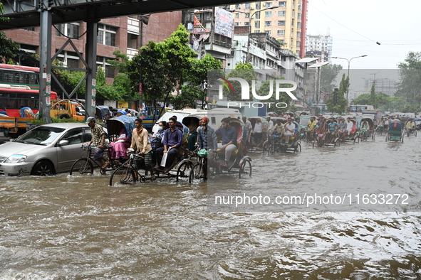 Vehicles and rickshaws try to drive with passengers through the waterlogged streets of Dhaka, Bangladesh, on October 3, 2024, after heavy mo...