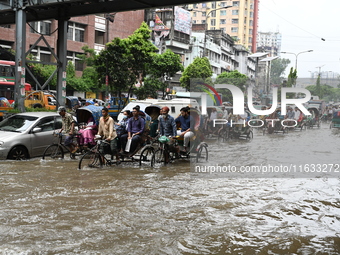 Vehicles and rickshaws try to drive with passengers through the waterlogged streets of Dhaka, Bangladesh, on October 3, 2024, after heavy mo...