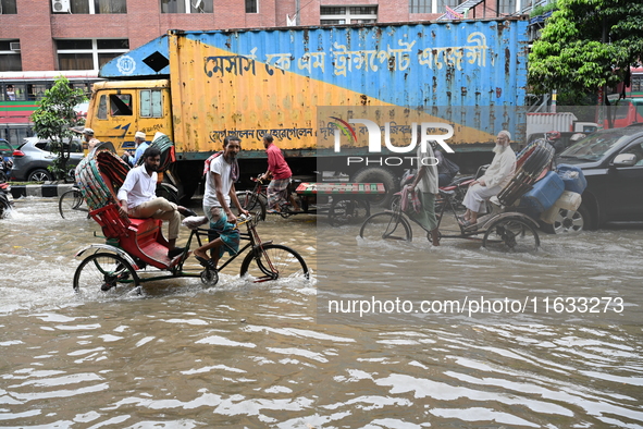 Vehicles and rickshaws try to drive with passengers through the waterlogged streets of Dhaka, Bangladesh, on October 3, 2024, after heavy mo...