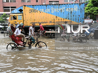 Vehicles and rickshaws try to drive with passengers through the waterlogged streets of Dhaka, Bangladesh, on October 3, 2024, after heavy mo...