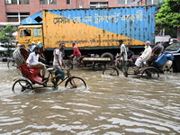 Vehicles and rickshaws try to drive with passengers through the waterlogged streets of Dhaka, Bangladesh, on October 3, 2024, after heavy mo...