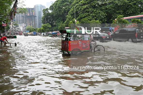 Vehicles and rickshaws try to drive with passengers through the waterlogged streets of Dhaka, Bangladesh, on October 3, 2024, after heavy mo...