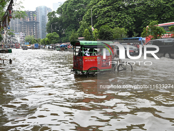 Vehicles and rickshaws try to drive with passengers through the waterlogged streets of Dhaka, Bangladesh, on October 3, 2024, after heavy mo...