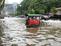 Vehicles and rickshaws try to drive with passengers through the waterlogged streets of Dhaka, Bangladesh, on October 3, 2024, after heavy mo...