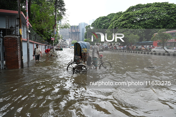 Vehicles and rickshaws try to drive with passengers through the waterlogged streets of Dhaka, Bangladesh, on October 3, 2024, after heavy mo...