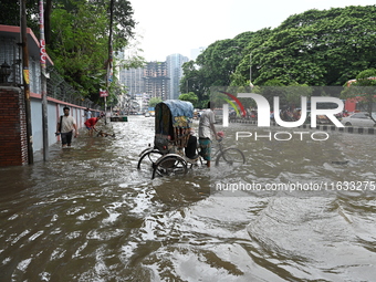 Vehicles and rickshaws try to drive with passengers through the waterlogged streets of Dhaka, Bangladesh, on October 3, 2024, after heavy mo...