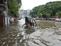 Vehicles and rickshaws try to drive with passengers through the waterlogged streets of Dhaka, Bangladesh, on October 3, 2024, after heavy mo...