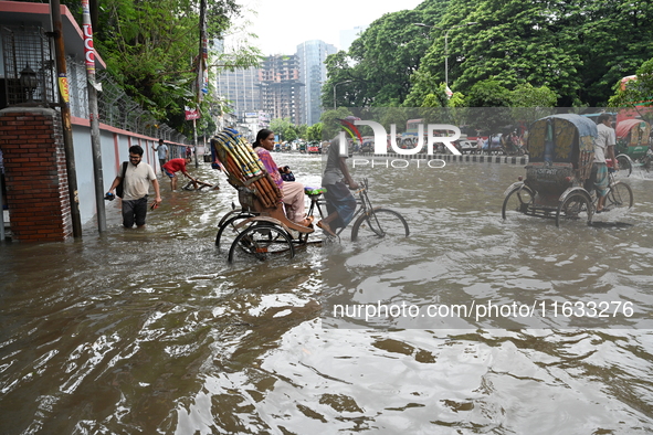 Vehicles and rickshaws try to drive with passengers through the waterlogged streets of Dhaka, Bangladesh, on October 3, 2024, after heavy mo...