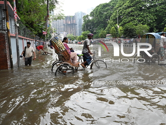 Vehicles and rickshaws try to drive with passengers through the waterlogged streets of Dhaka, Bangladesh, on October 3, 2024, after heavy mo...