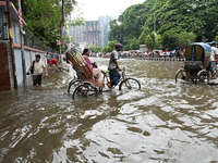 Vehicles and rickshaws try to drive with passengers through the waterlogged streets of Dhaka, Bangladesh, on October 3, 2024, after heavy mo...